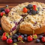 Slice of berry cake being removed from mixed berry cake