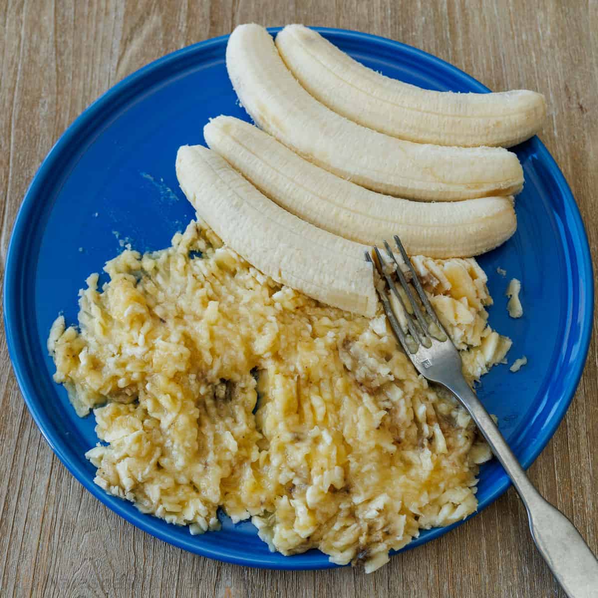 Mashing bananas on a plate with a fork