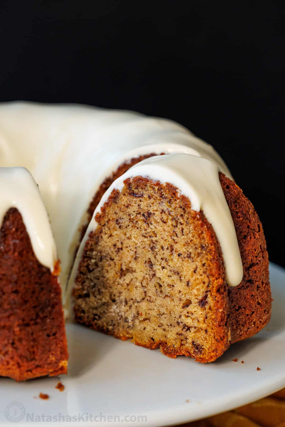 A slice removed from a Banana Bundt Cake glazed with cream cheese glaze