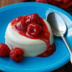 Panna cotta with berry sauce on a blue plate