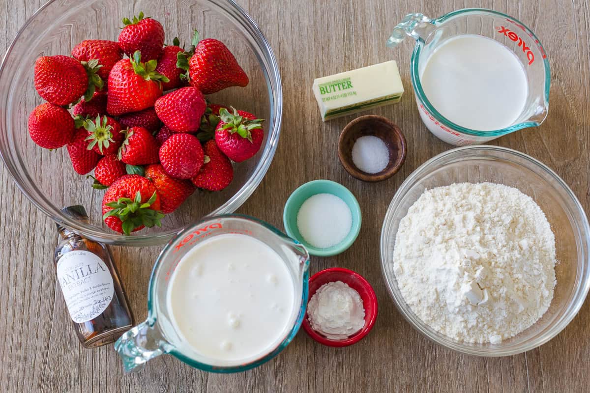 ingredients for strawberry shortcake including strawberries, vanilla, heavy whipping cream, sugar, salt, butter, milk and flour