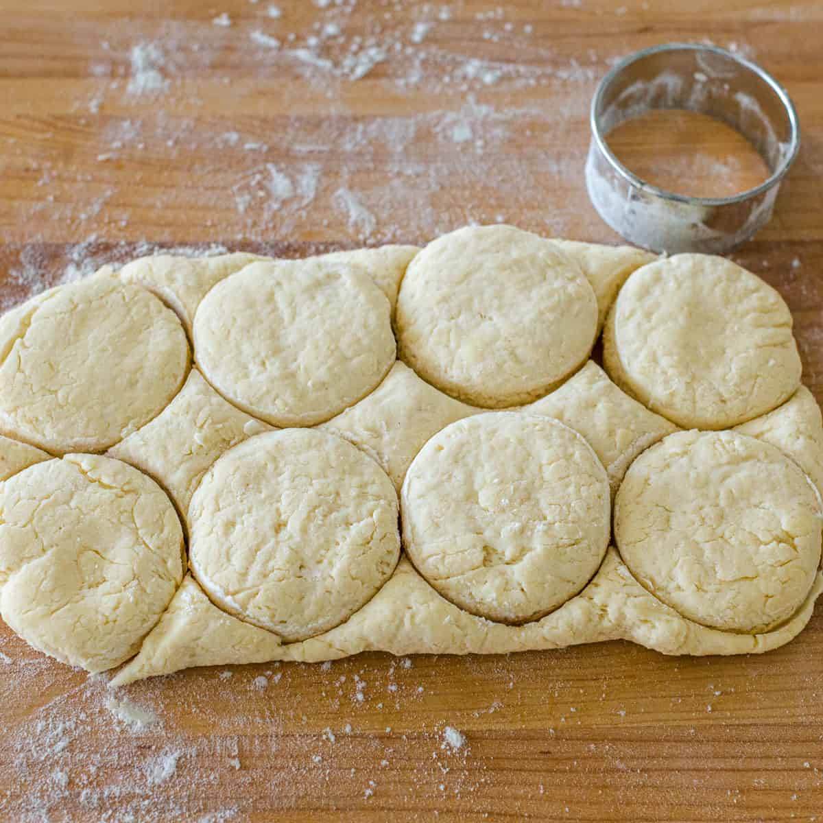 eight shortbread biscuits cut with a biscuit cutter on a wooden cutting board