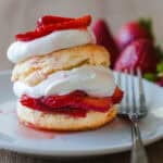 strawberry shortcake on a plate with a fork and strawberry garnish