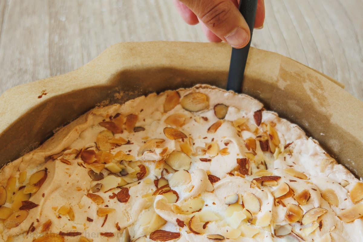 Sliced almonds sprinkled on top of the meringue layer of Himmelstorte before baking in the oven