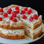 Himmelstorte layered with cake, whipped cream, and raspberries on a cake platter sliced to serve